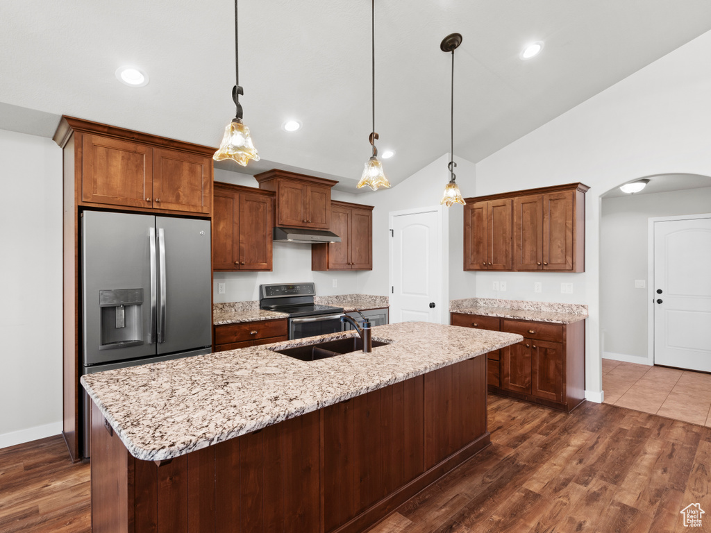 Kitchen featuring hanging light fixtures, lofted ceiling, a kitchen island with sink, and appliances with stainless steel finishes