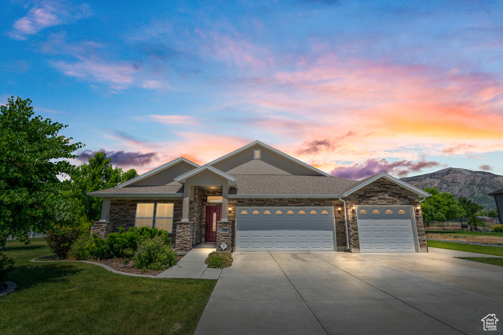 View of front facade featuring a garage, a mountain view, and a lawn