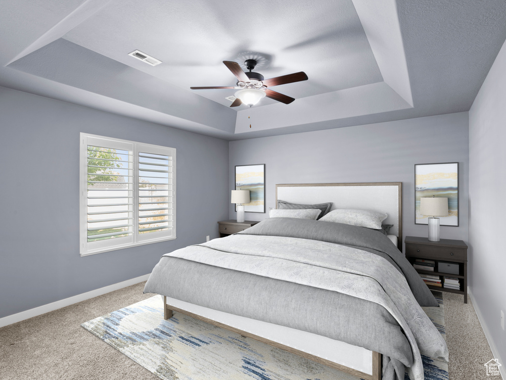 Carpeted bedroom with ceiling fan and a tray ceiling