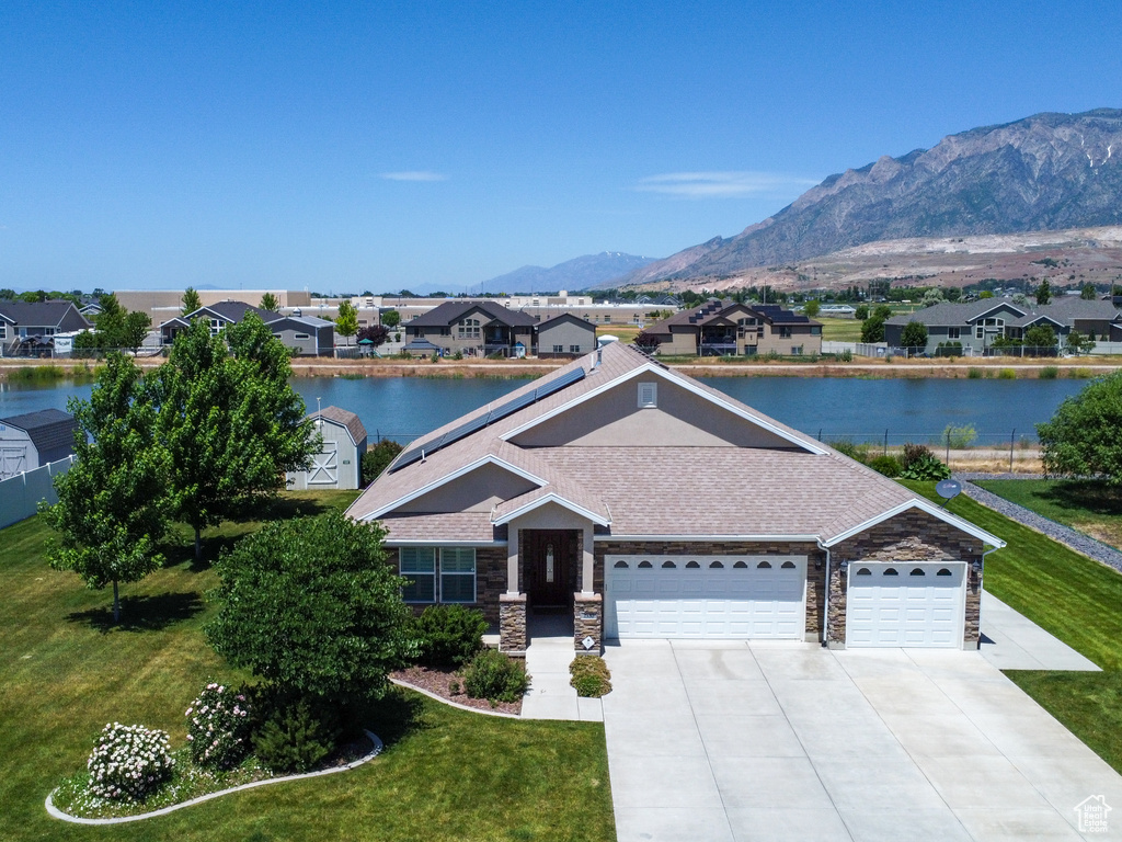 View of front of property featuring a front yard, a water and mountain view, and a garage