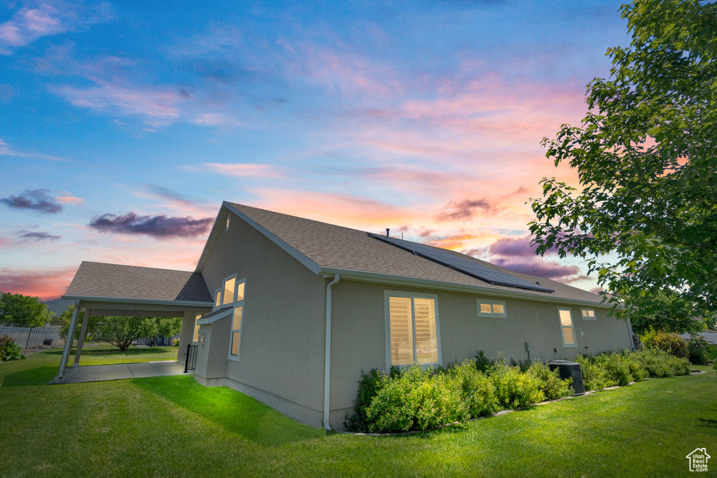 Property exterior at dusk featuring a patio and a lawn