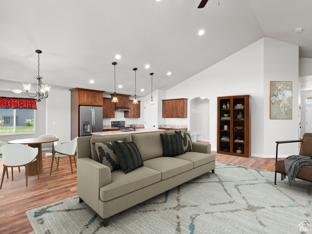 Living room featuring high vaulted ceiling, sink, ceiling fan with notable chandelier, and light hardwood / wood-style flooring