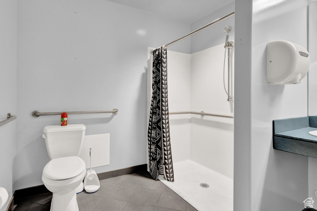 Bathroom with tile floors, toilet, and a shower with shower curtain