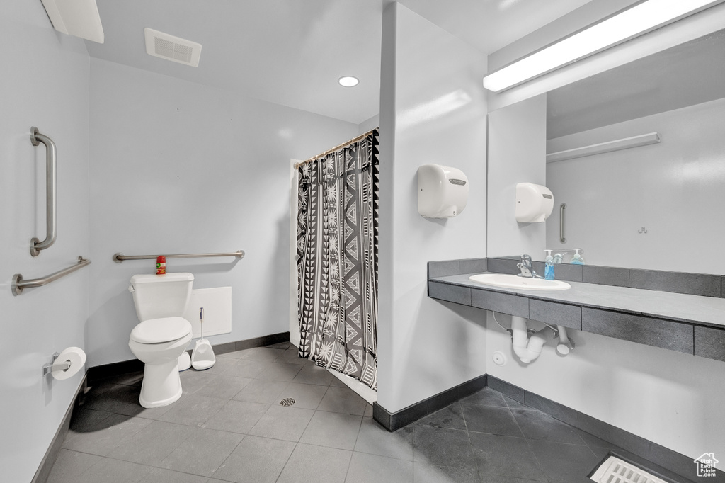 Bathroom featuring toilet, tile floors, and sink