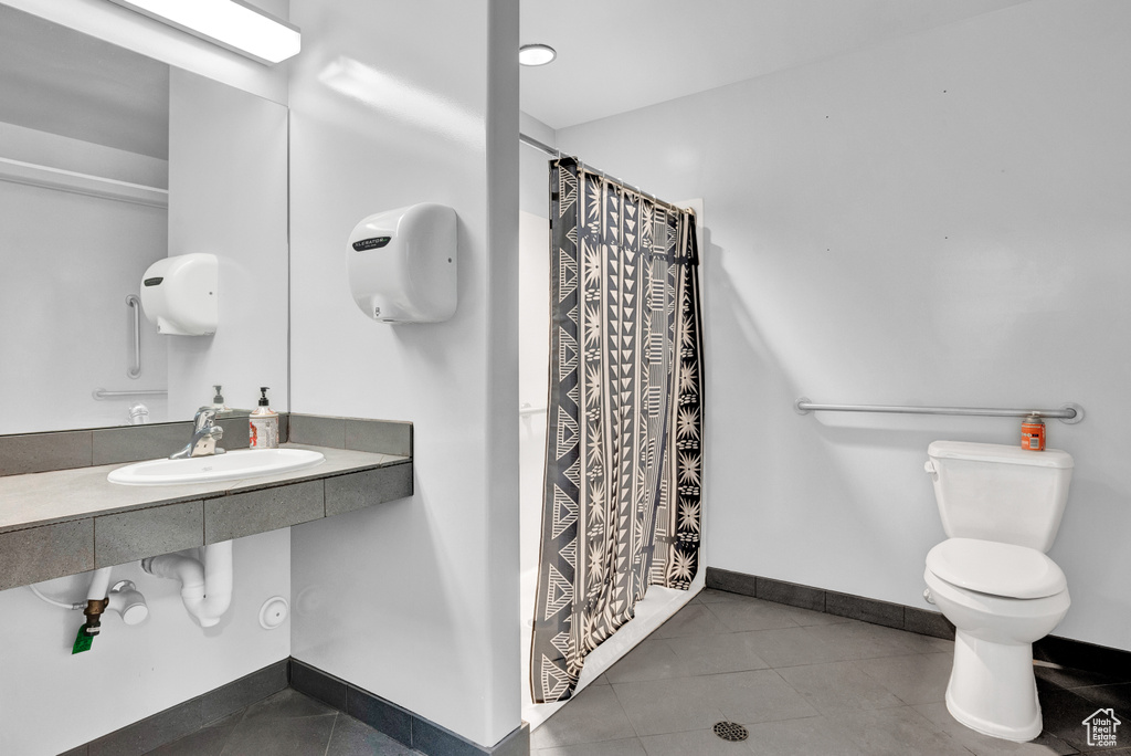 Bathroom with toilet, tile floors, and sink