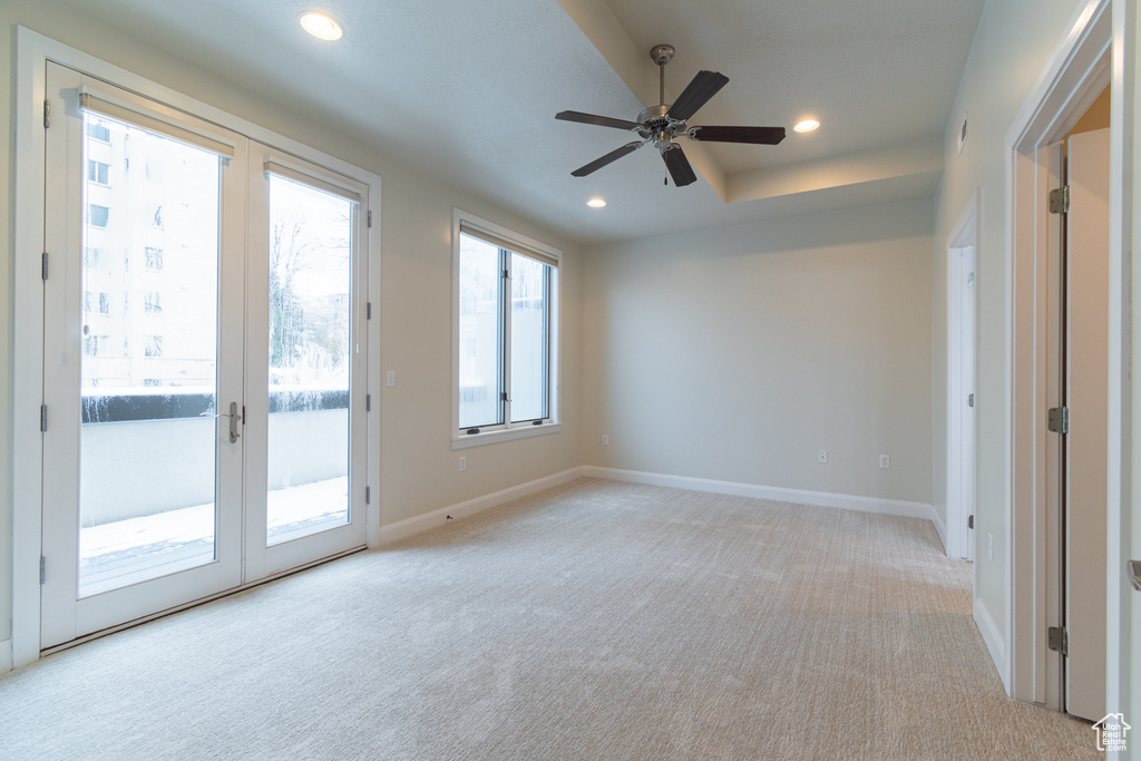 Carpeted empty room featuring ceiling fan and french doors