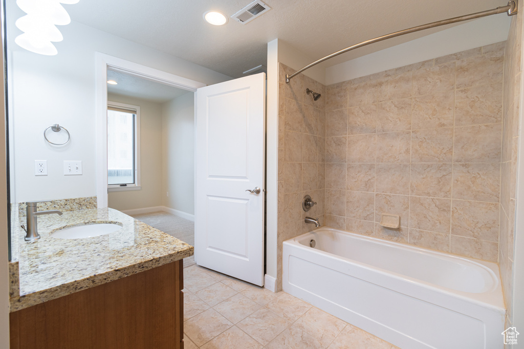 Bathroom with tile flooring, tiled shower / bath combo, and vanity