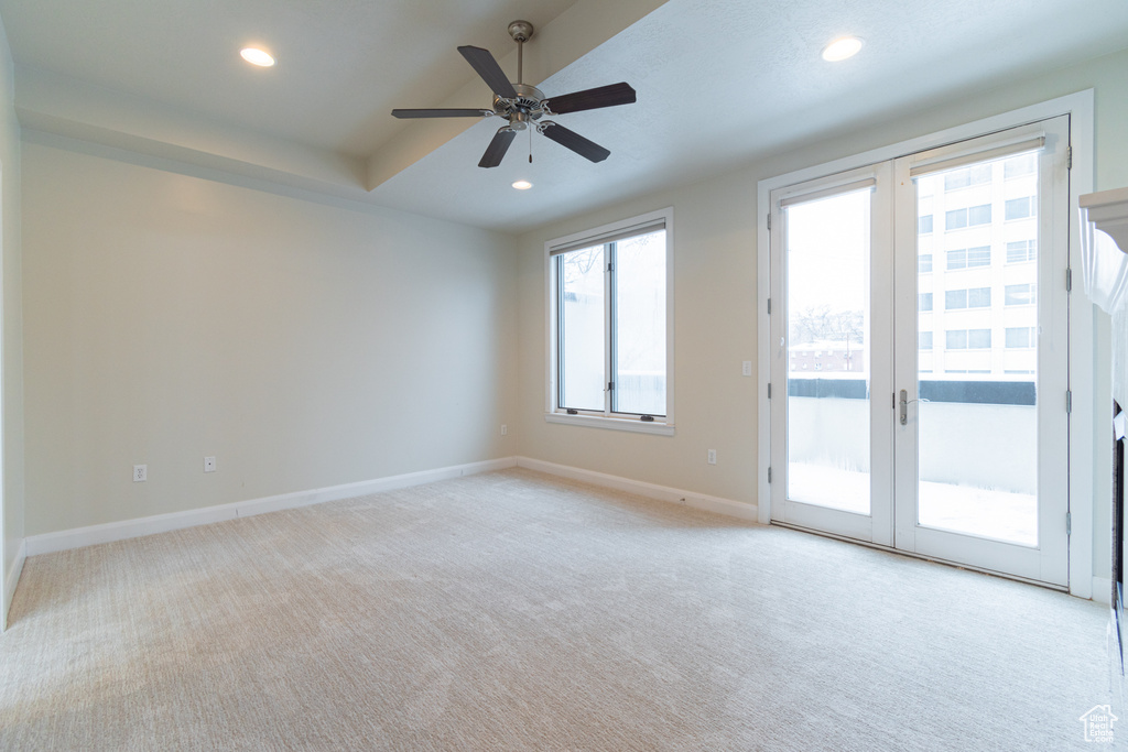 Carpeted spare room featuring ceiling fan and french doors