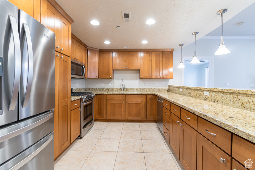 Kitchen featuring crown molding, hanging light fixtures, appliances with stainless steel finishes, sink, and light tile floors