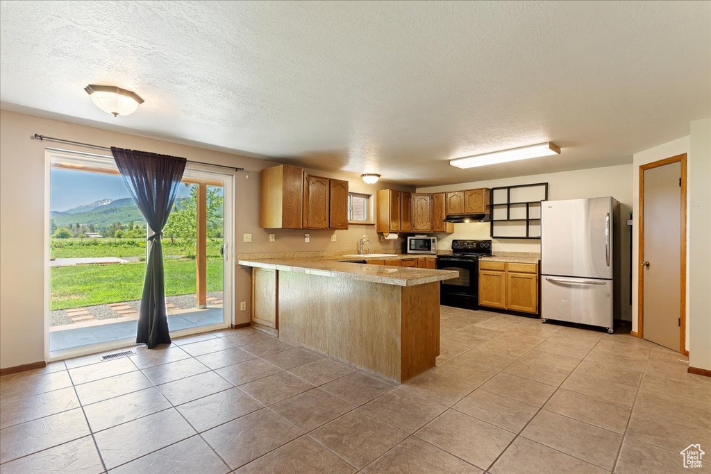 Kitchen with stainless steel appliances, kitchen peninsula, light tile flooring, and sink