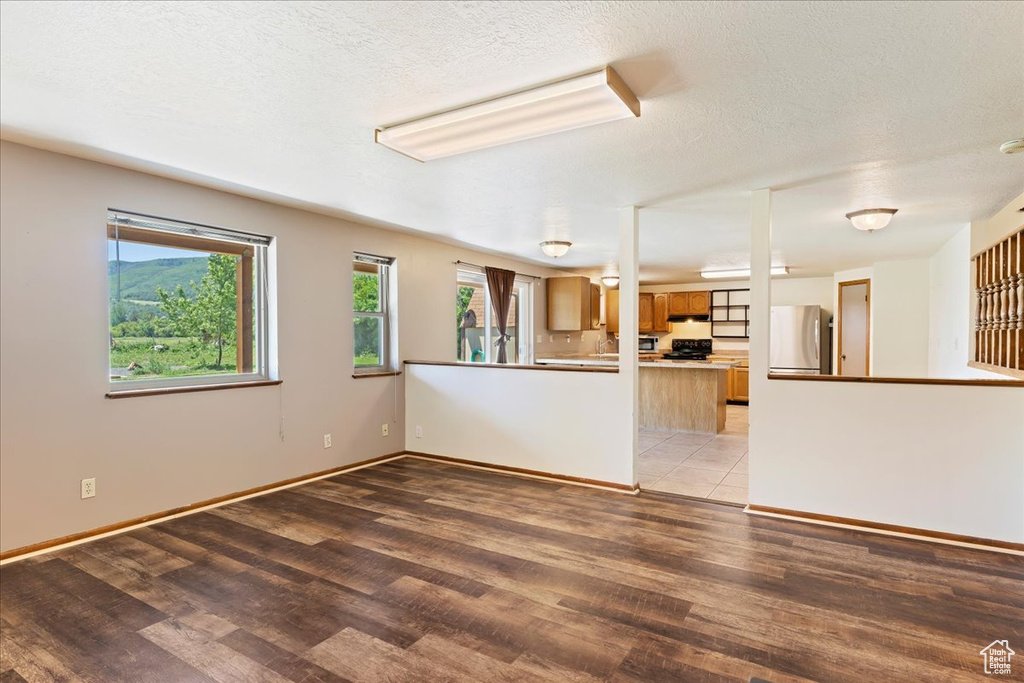 Unfurnished living room featuring hardwood / wood-style flooring and a textured ceiling