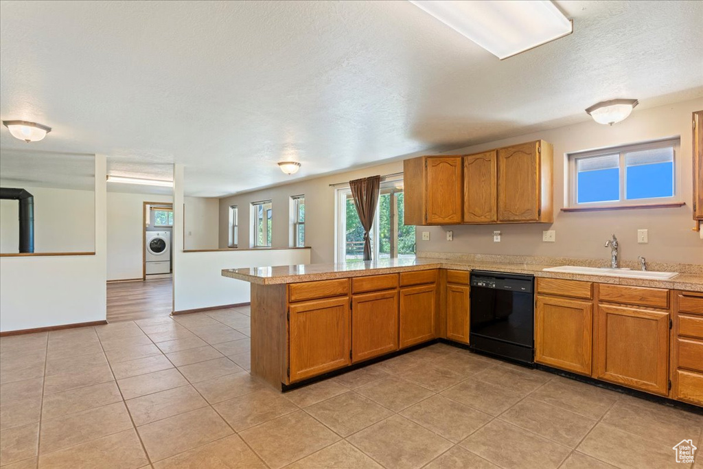 Kitchen with washer / dryer, kitchen peninsula, dishwasher, sink, and light tile floors