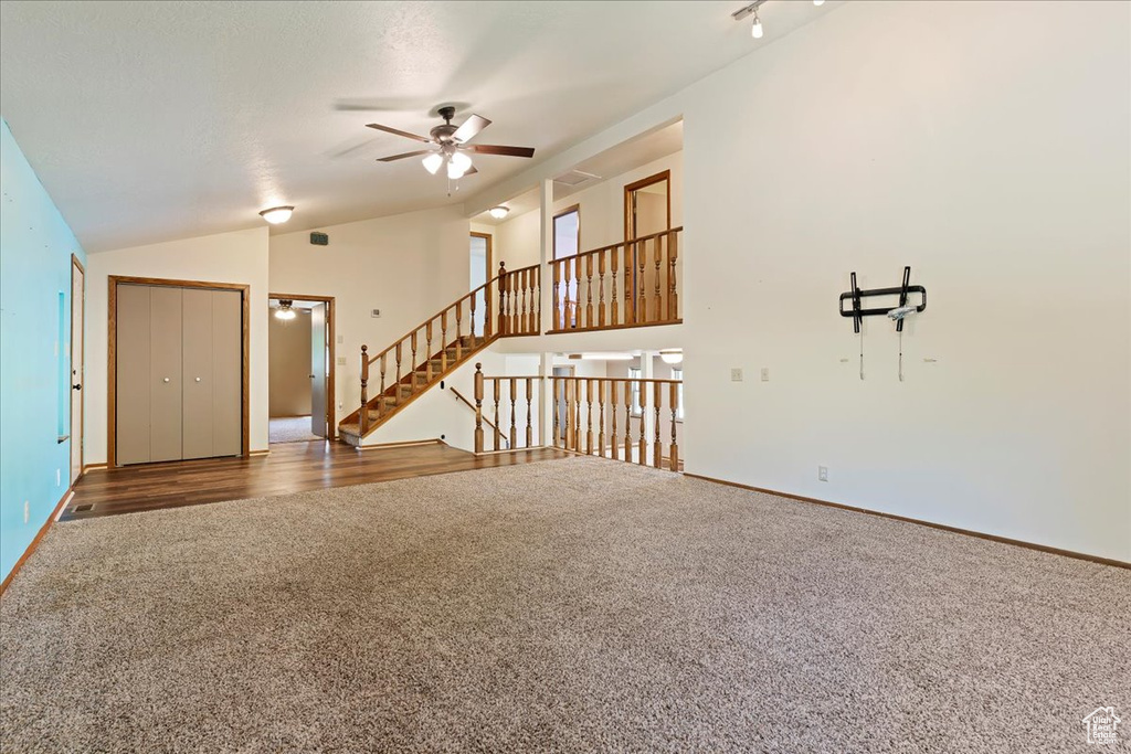 Unfurnished living room featuring high vaulted ceiling, ceiling fan, and carpet floors