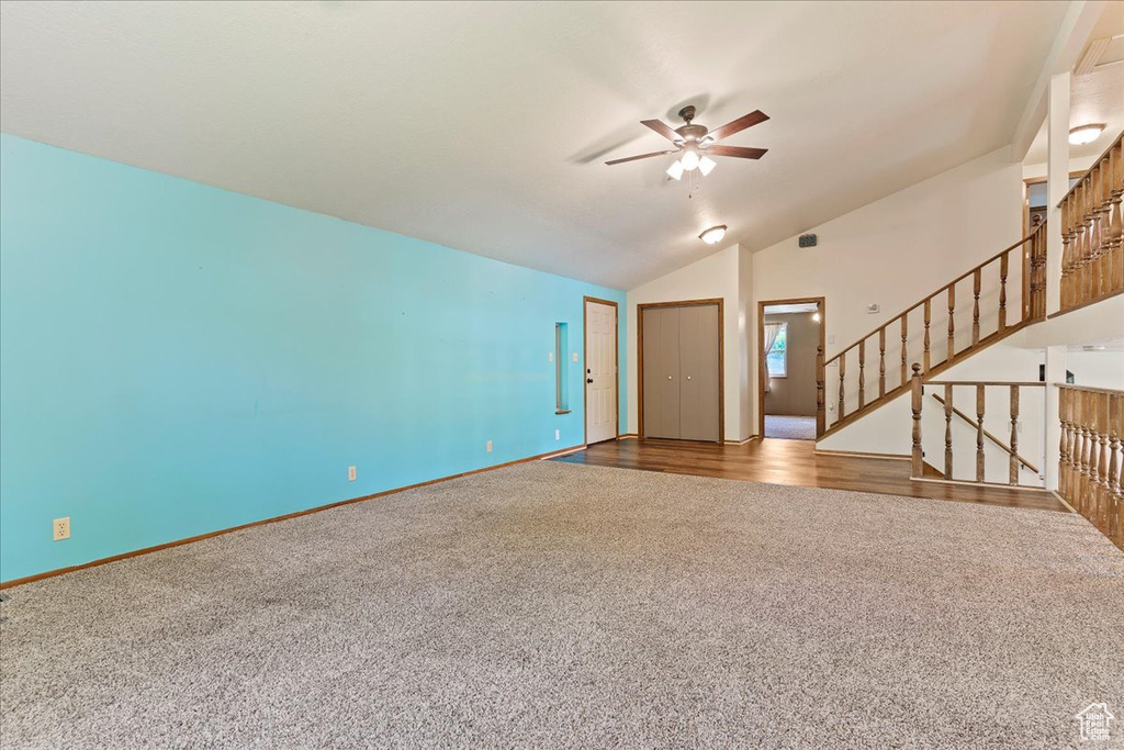 Unfurnished living room featuring ceiling fan, vaulted ceiling, and hardwood / wood-style flooring