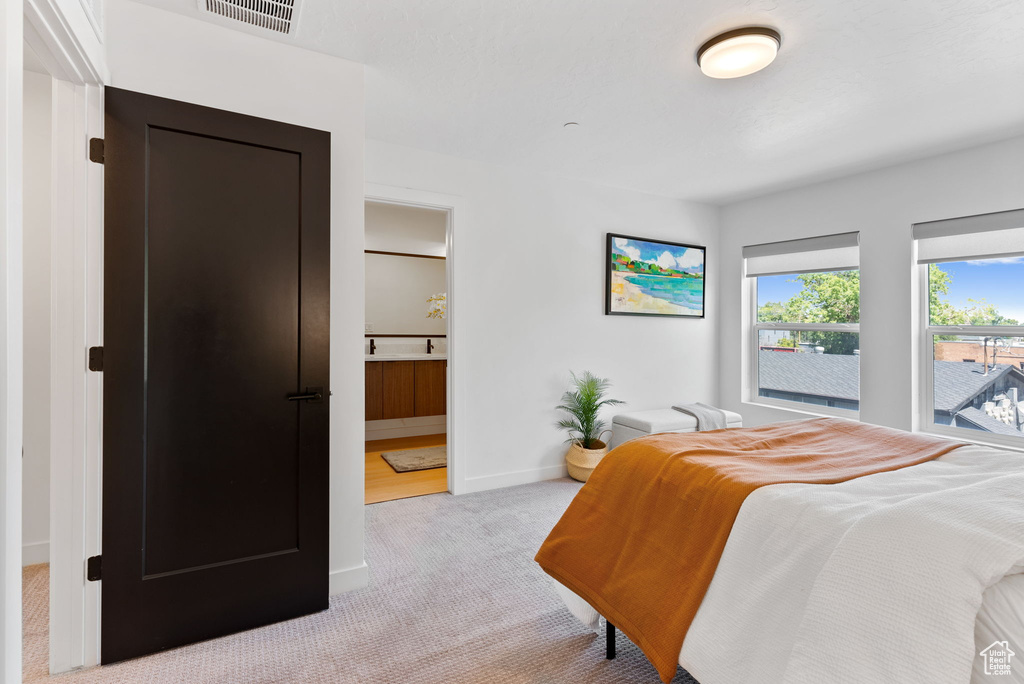 Bedroom with light colored carpet and ensuite bathroom