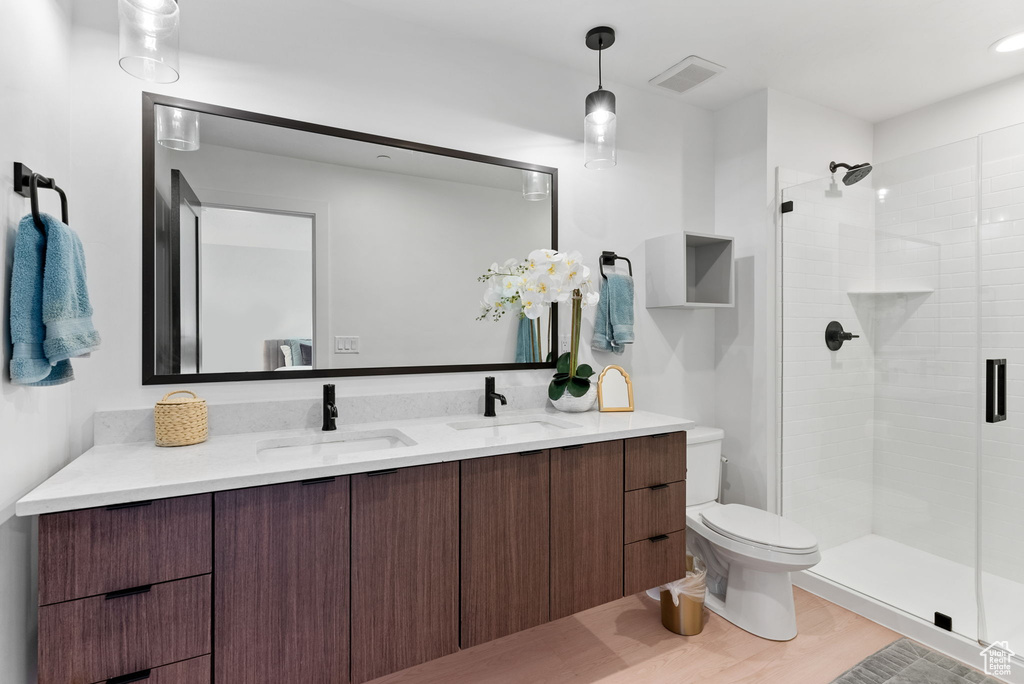 Bathroom featuring toilet, walk in shower, vanity, and hardwood / wood-style flooring