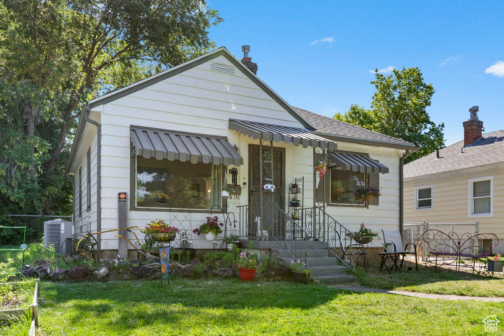 Bungalow featuring a front yard and central AC unit