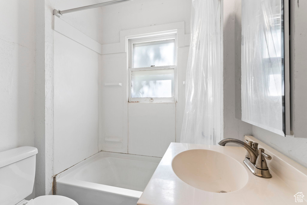 Full bathroom with vanity with extensive cabinet space, toilet, and shower / tub combo with curtain