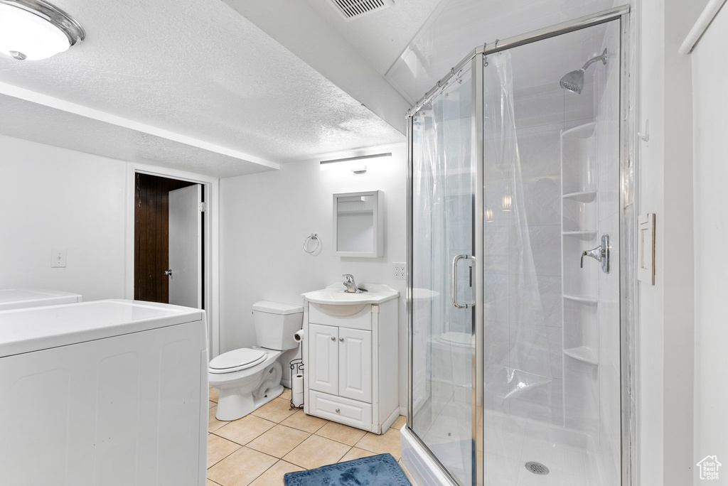 Bathroom featuring walk in shower, a textured ceiling, tile floors, toilet, and vanity