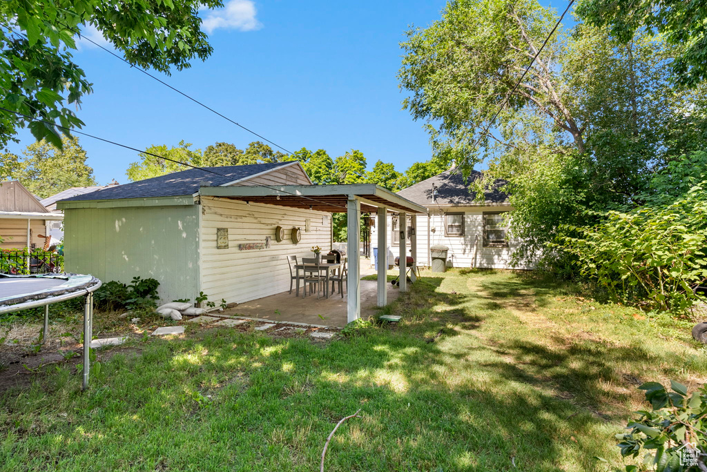 Back of house with a patio, a trampoline, and a yard