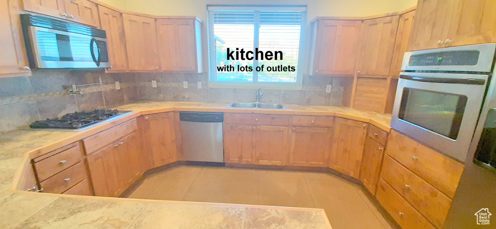 Kitchen with decorative backsplash, light tile patterned floors, appliances with stainless steel finishes, and sink