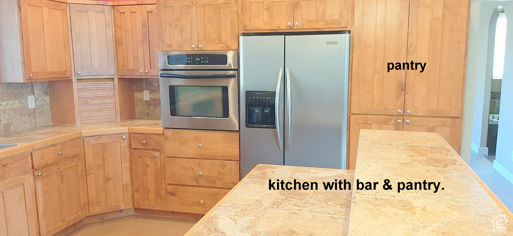 Kitchen with stainless steel appliances, backsplash, and light brown cabinetry