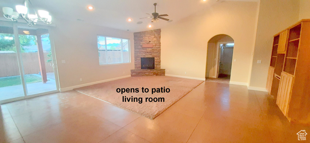 Unfurnished living room featuring a fireplace, tile patterned flooring, ceiling fan with notable chandelier, and vaulted ceiling