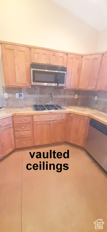 Kitchen with decorative backsplash, appliances with stainless steel finishes, vaulted ceiling, and light brown cabinets