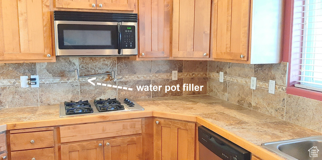 Kitchen featuring decorative backsplash and appliances with stainless steel finishes