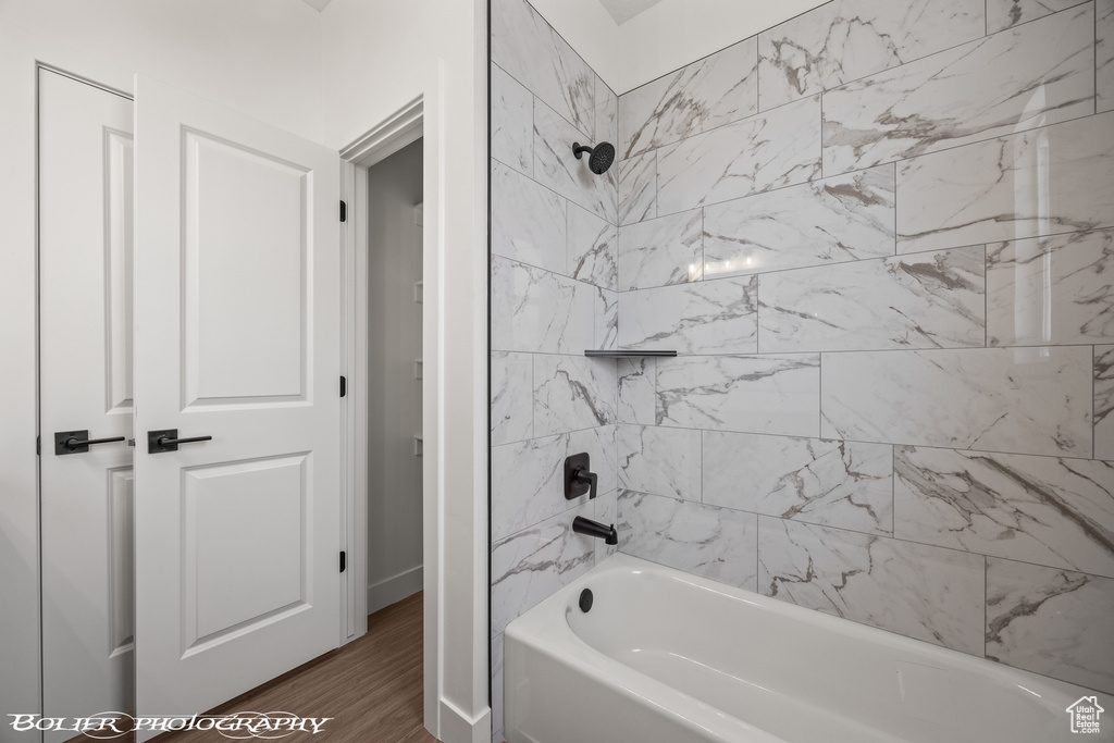 Bathroom with wood-type flooring and tiled shower / bath combo