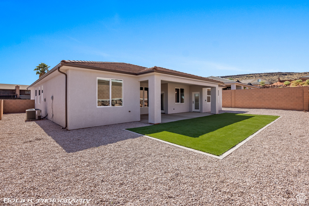 Back of house featuring a yard, central AC unit, and a patio area