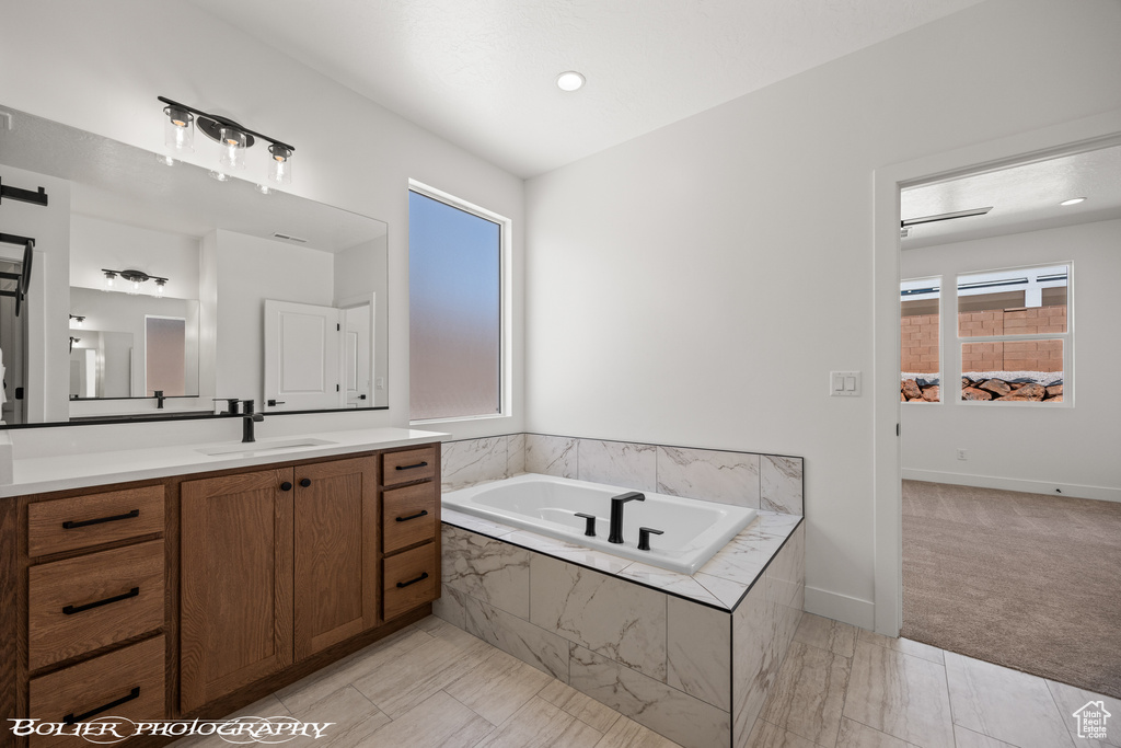 Bathroom featuring a relaxing tiled tub and vanity