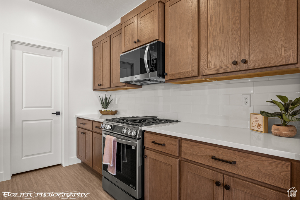 Kitchen featuring appliances with stainless steel finishes, decorative backsplash, and light hardwood / wood-style floors