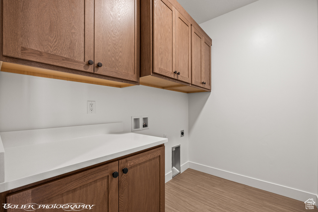 Laundry area featuring hookup for a washing machine, light hardwood / wood-style flooring, electric dryer hookup, and cabinets