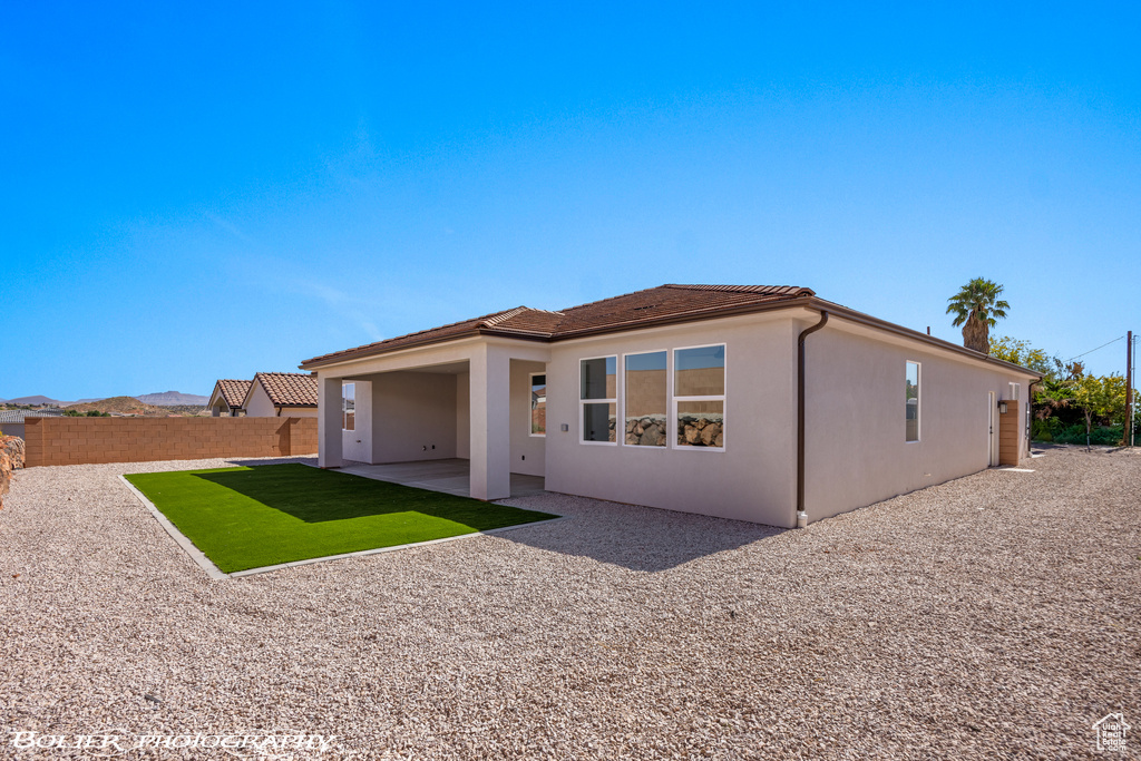 Rear view of house with a lawn and a patio