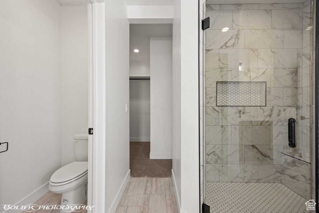 Bathroom featuring a shower with shower door and toilet