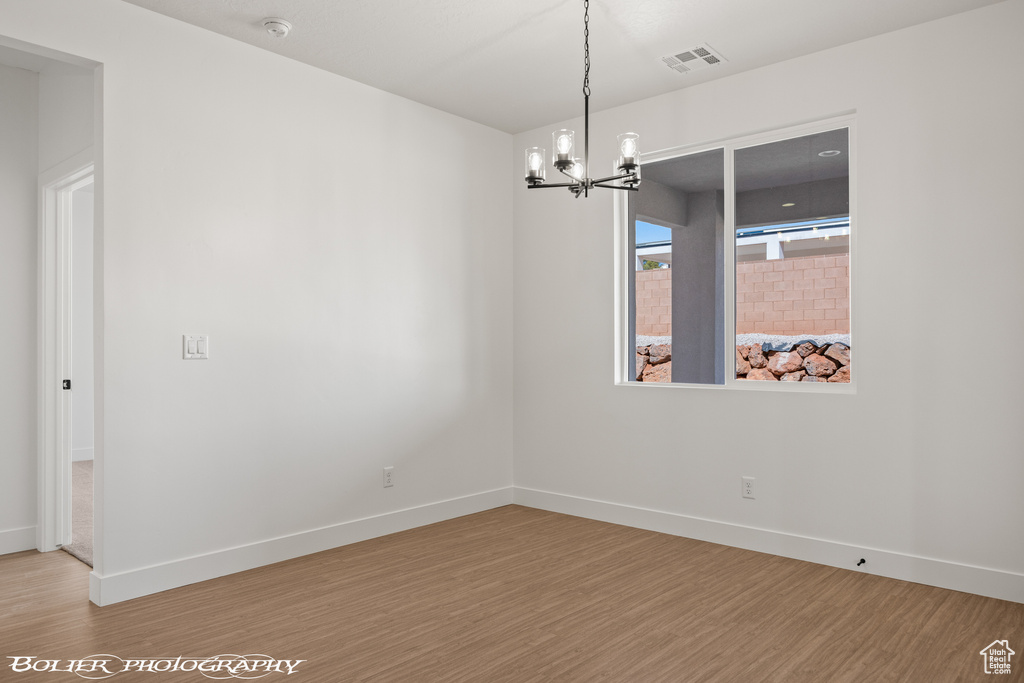 Unfurnished room with a chandelier and hardwood / wood-style flooring