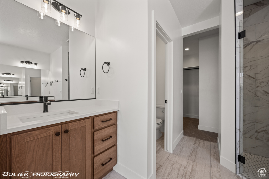 Bathroom featuring walk in shower, vanity, hardwood / wood-style floors, and toilet