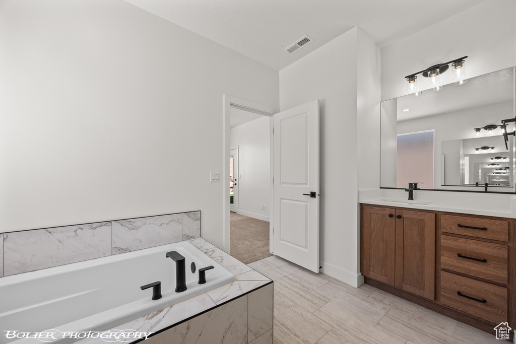 Bathroom featuring vanity and tiled bath