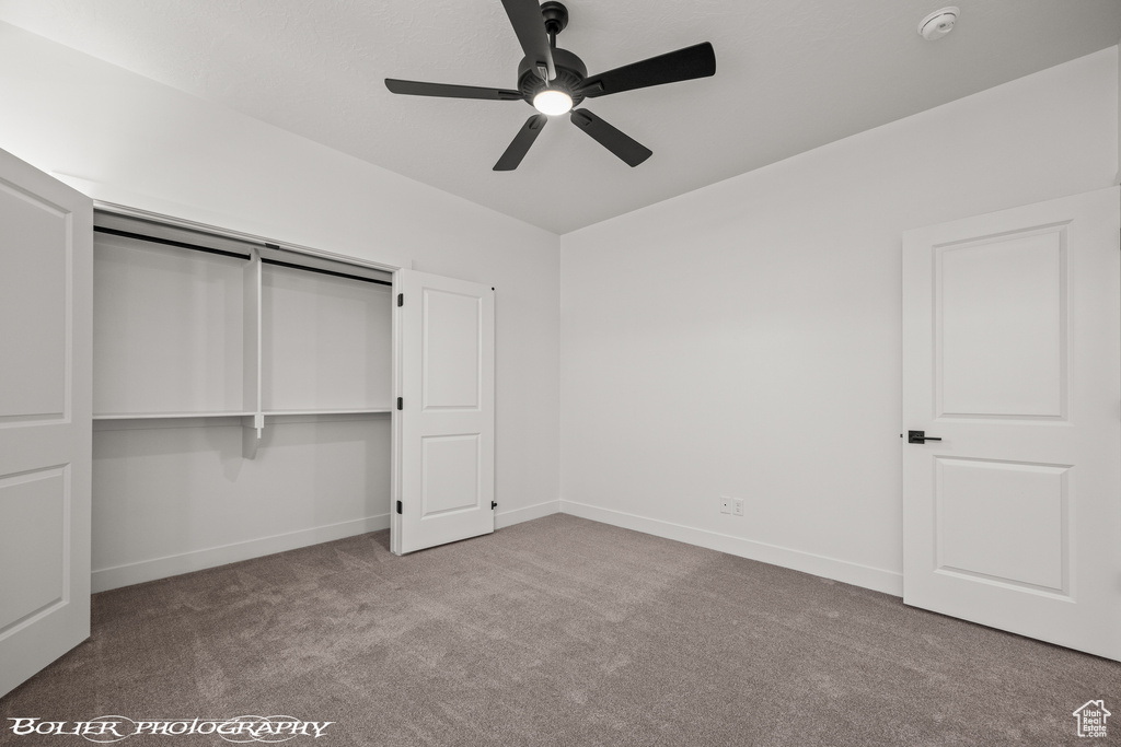 Unfurnished bedroom featuring ceiling fan, a closet, and light carpet