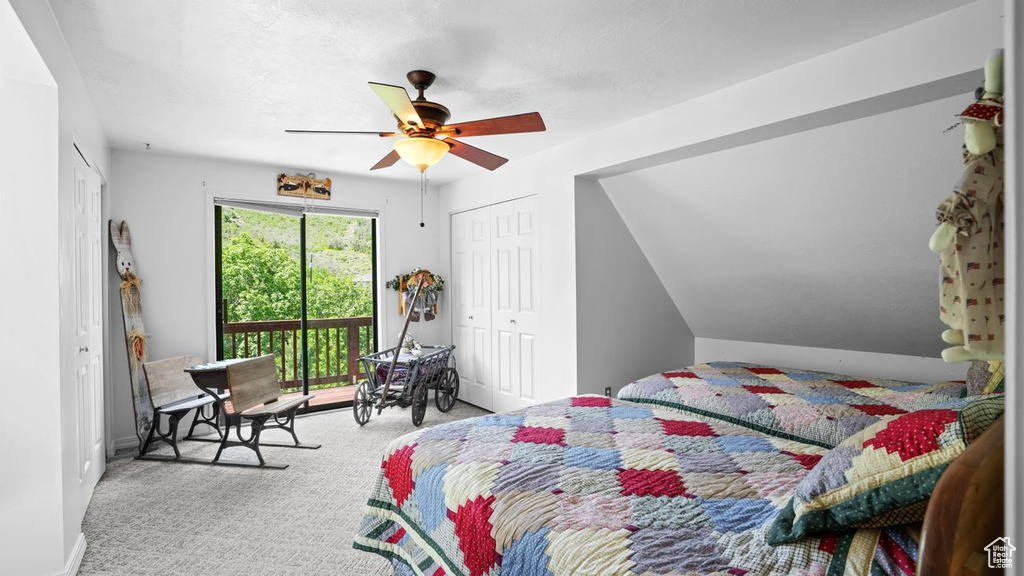 Carpeted bedroom with a closet, ceiling fan, and lofted ceiling