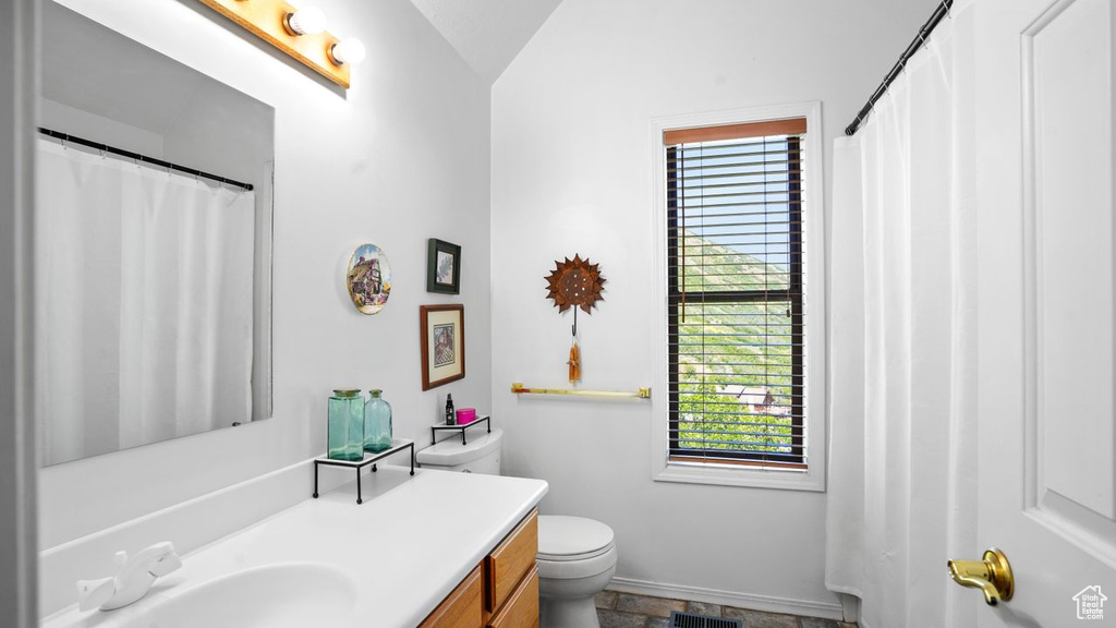 Bathroom featuring tile floors, toilet, lofted ceiling, and oversized vanity