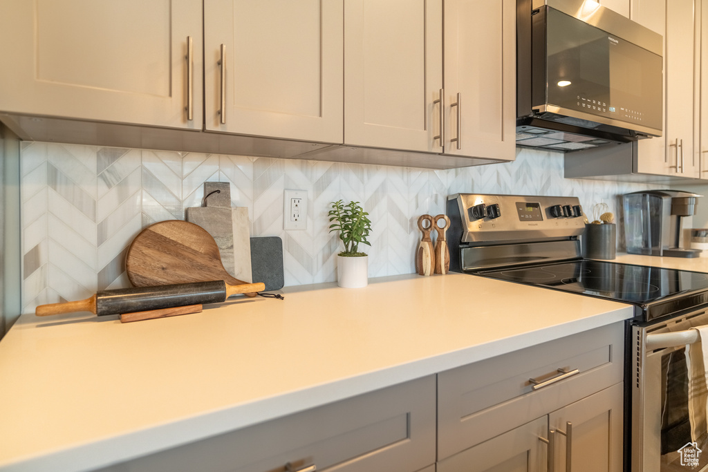 Kitchen with electric range, tasteful backsplash, and gray cabinets