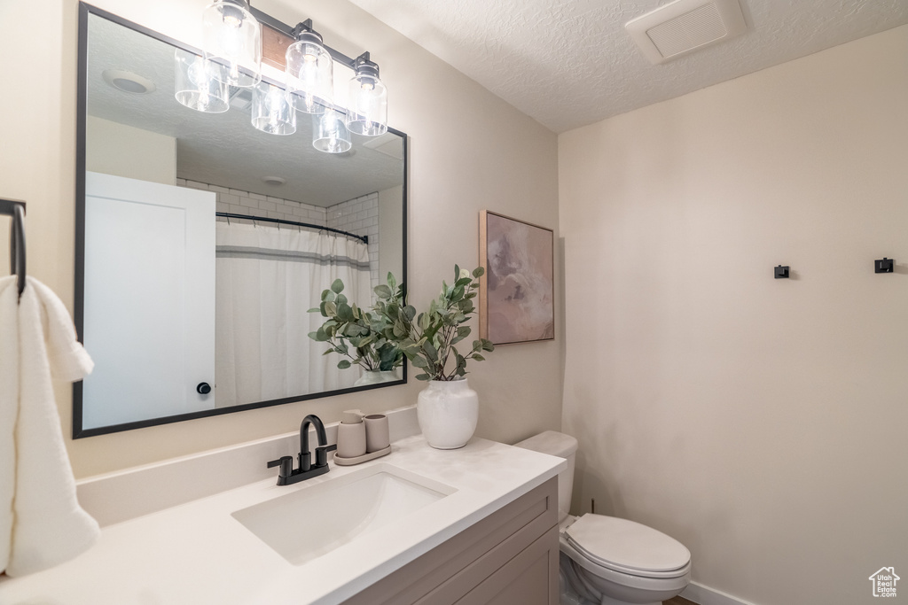 Bathroom with vanity, toilet, and a textured ceiling