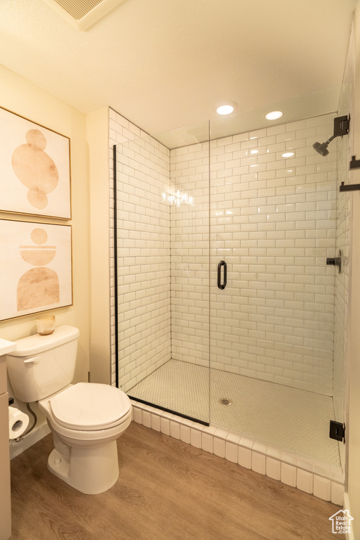 Bathroom featuring walk in shower, hardwood / wood-style flooring, toilet, and a notable chandelier