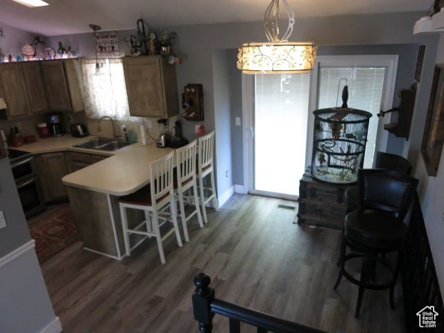 Kitchen featuring a breakfast bar area, hanging light fixtures, sink, and dark hardwood / wood-style floors