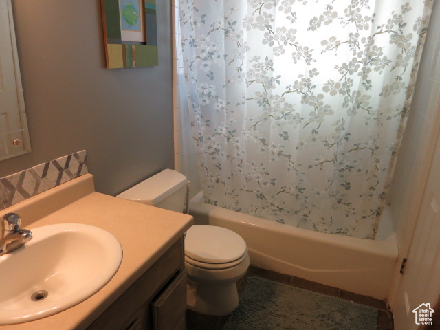 Full bathroom with shower / bath combo, large vanity, and toilet