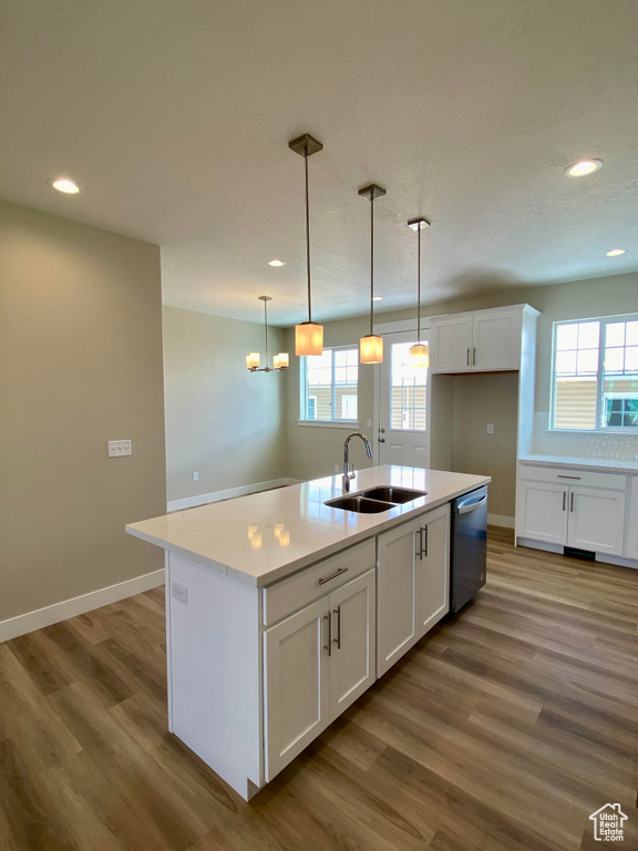 Kitchen featuring sink, white cabinets, wood-type flooring, and a center island with sink