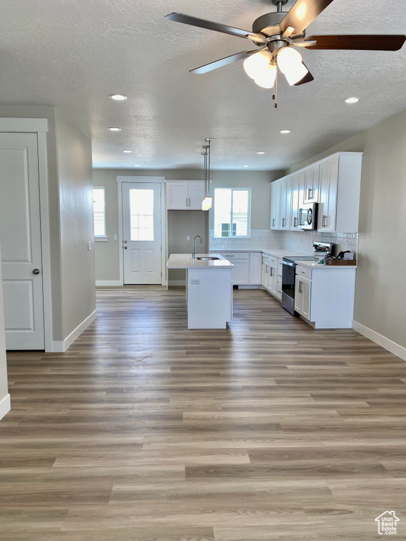 Kitchen featuring appliances with stainless steel finishes, a healthy amount of sunlight, wood-type flooring, and pendant lighting