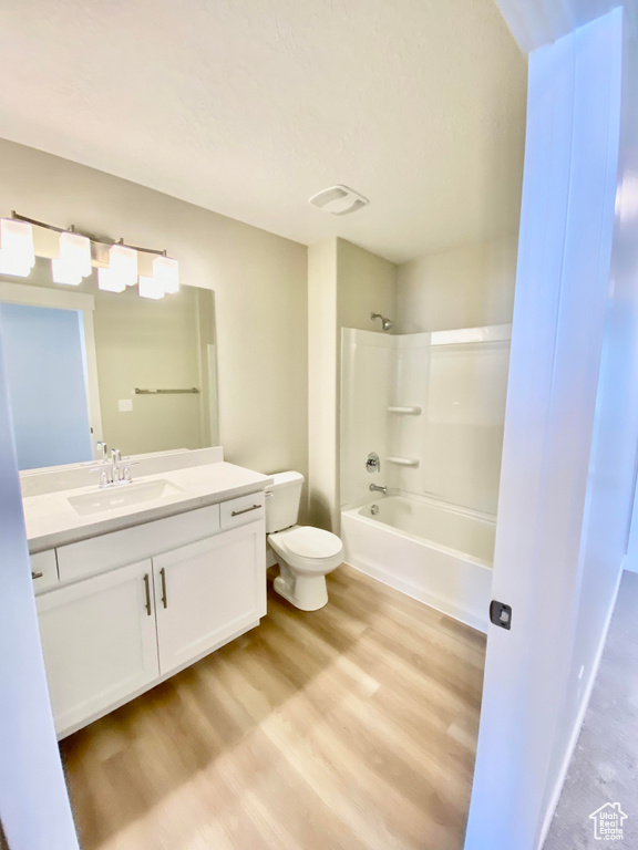 Full bathroom with wood-type flooring, shower / tub combination, toilet, and vanity